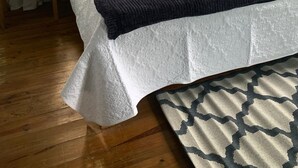 Une chambre à coucher comprenant un lit, deux tables de chevet, une fenêtre et un appareil de climatisation.