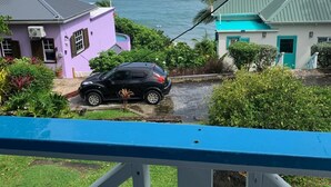 Un quartier résidentiel avec des maisons, une voiture et une vue sur l’océan.