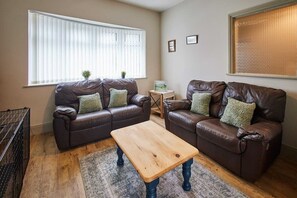 A living room with two brown leather sofas, a wooden coffee table, and a patterned rug.