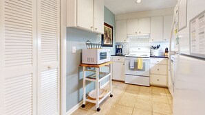 A compact kitchen with white cabinets, a microwave, an oven, and a refrigerator.