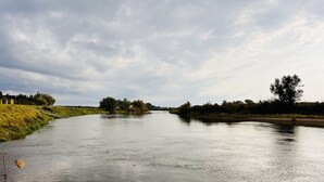 Un fiume con acque calme, rive erbose e alberi sullo sfondo.