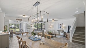 Un salon spacieux avec une grande table à manger en bois, des sièges confortables et un lustre.