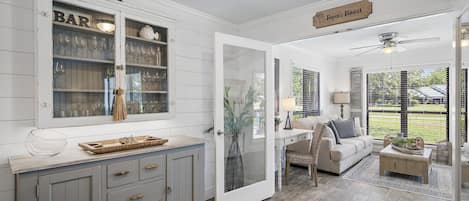 A kitchen with a bar area, a dining area with a sofa, and a view of the outdoors.
