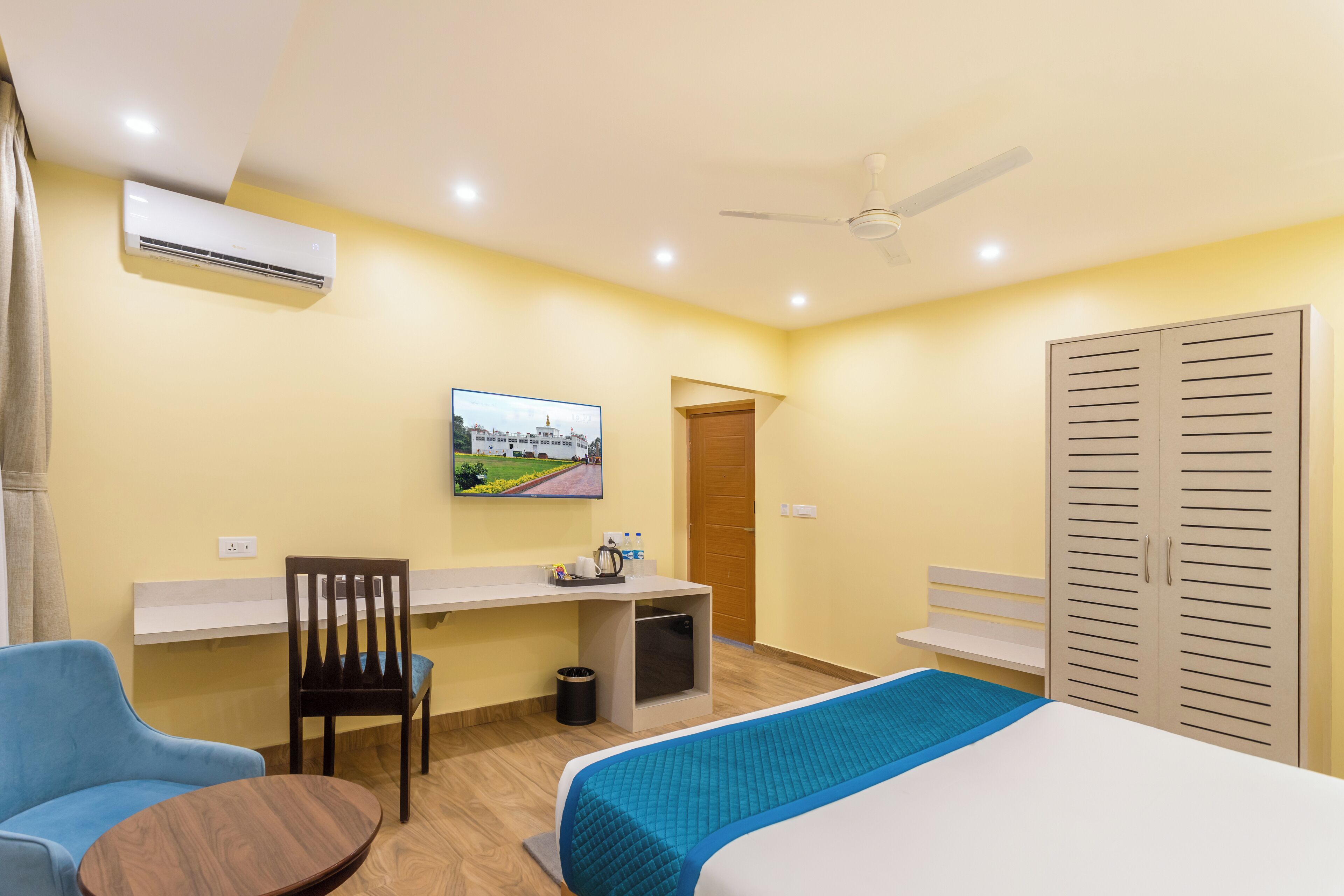 A hotel room with a bed, a desk, a chair, a TV, and a wardrobe.