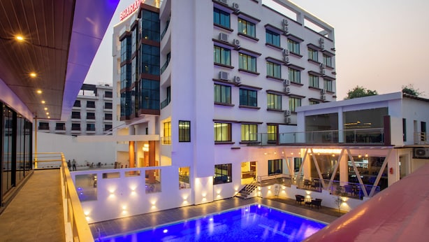 Un hotel moderno con zona de piscina, varias plantas y un cartel llamativo.