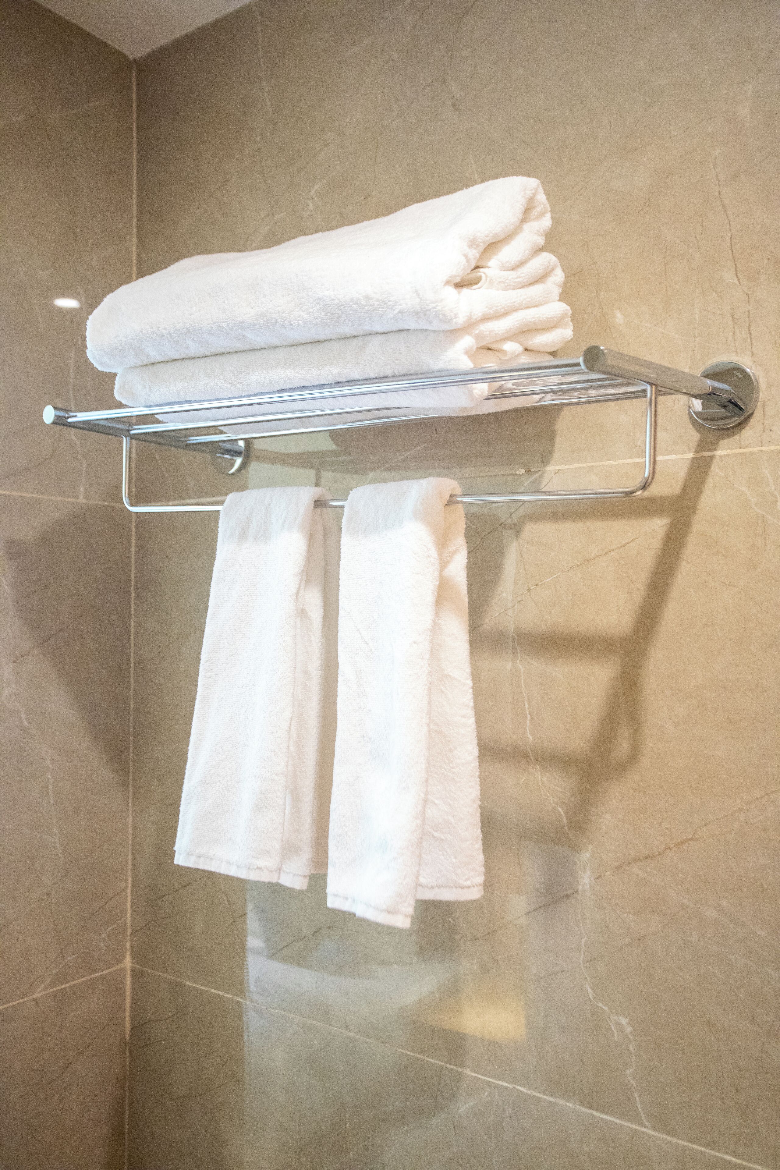 Un baño con toallero y toallas dobladas.