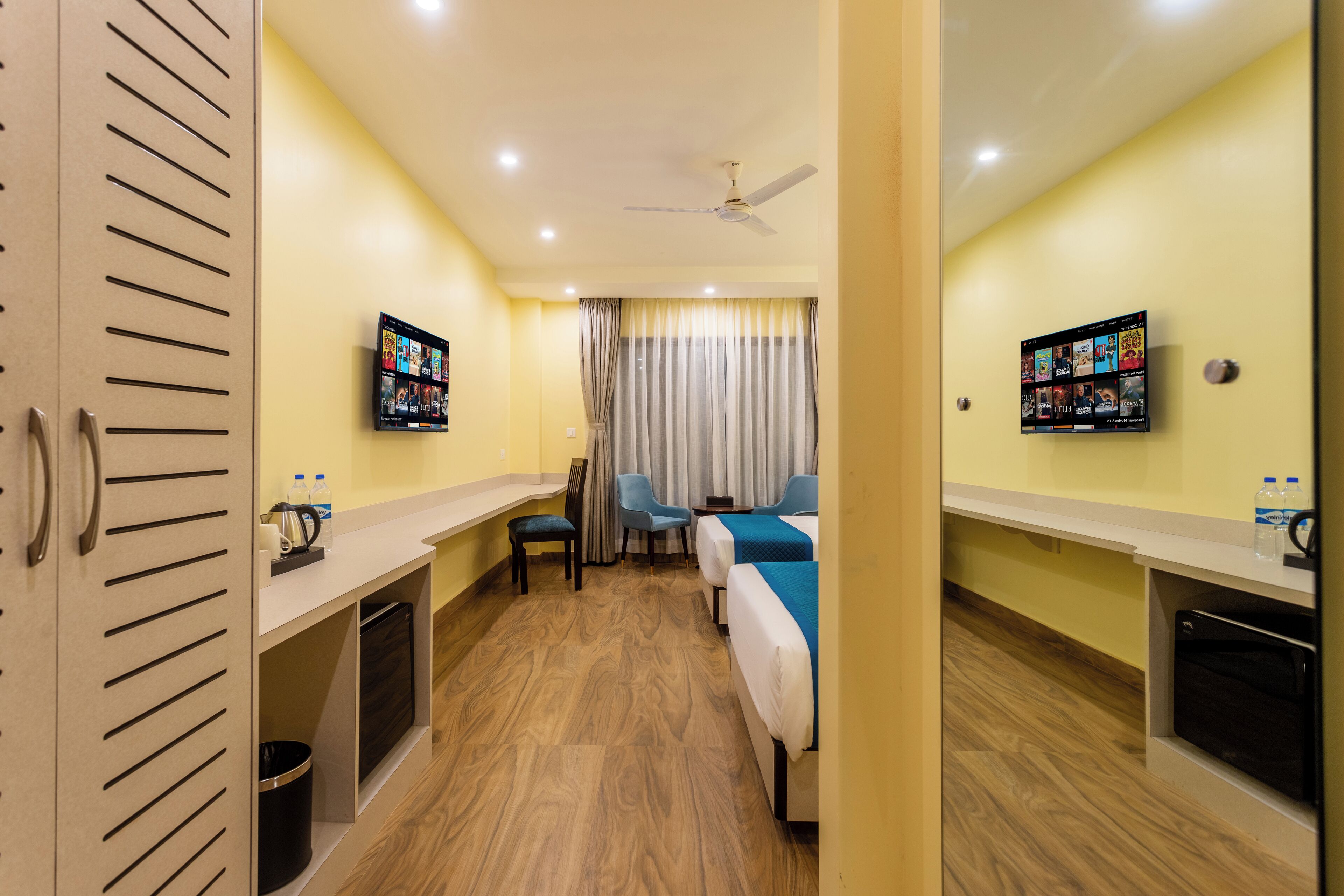 A hotel room with a bed, a desk, a television, and a ceiling fan.