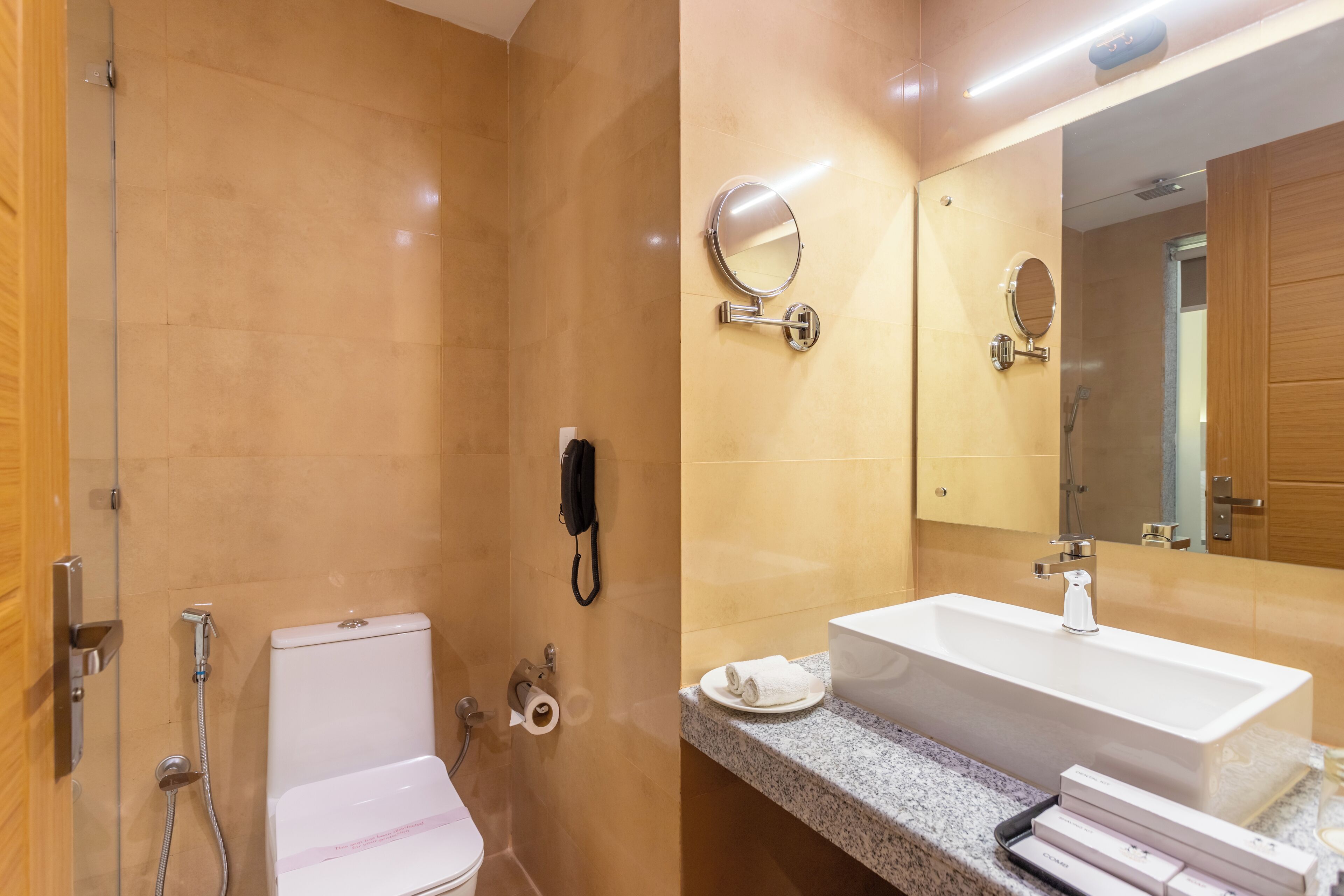 Un baño con inodoro, bidé, lavamanos, espejo y perchero para toallas.