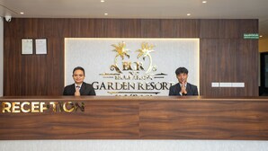 Una recepción de hotel con detalles de madera y un letrero que dice 'Garden Resort'.