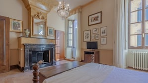 A bedroom with a large bed, a fireplace, a television, and framed pictures on the wall. - Miranda s Home in Varenna (Varenna)
