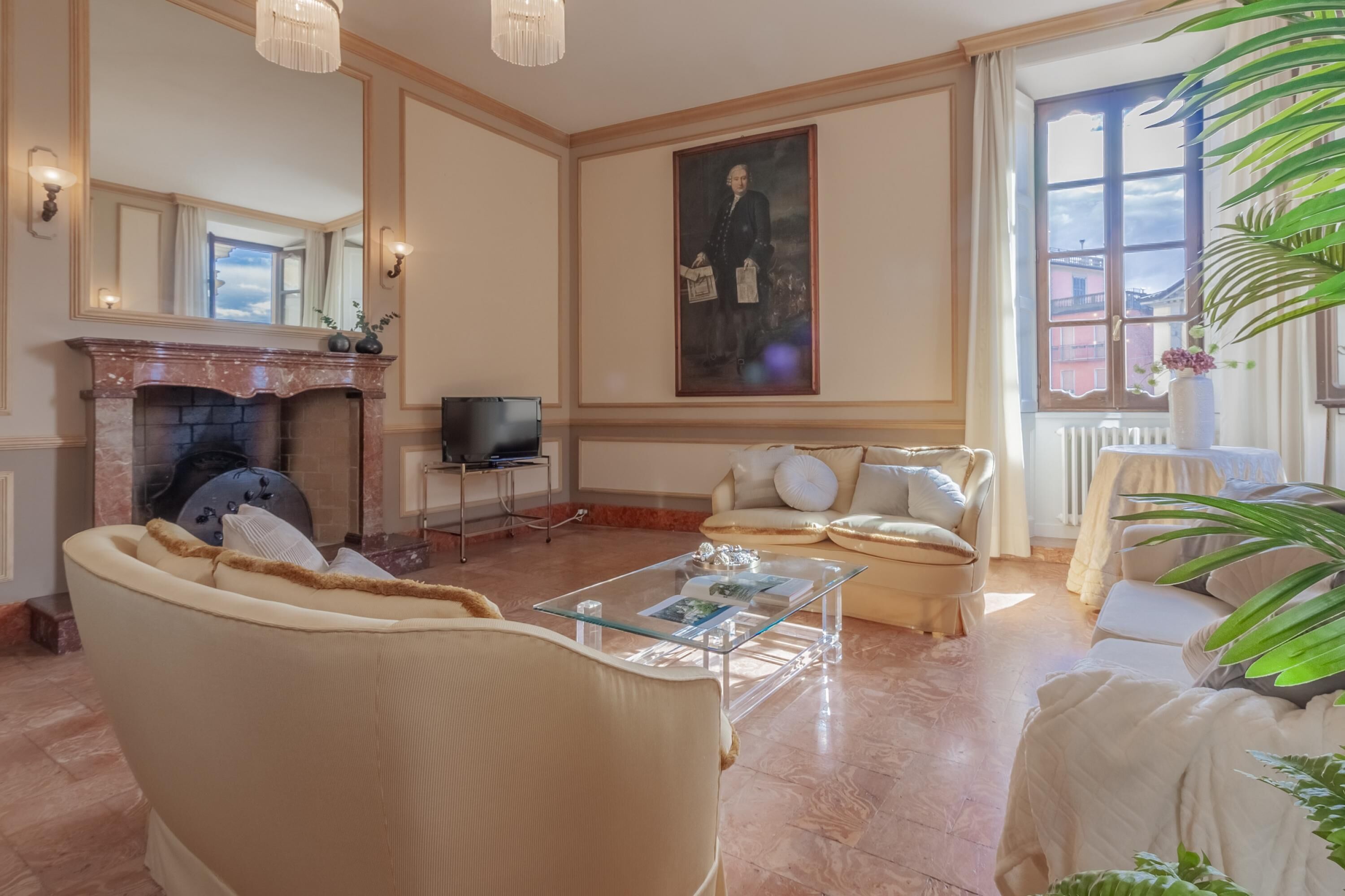 A spacious living room with a fireplace, a large portrait, and a comfortable seating area.