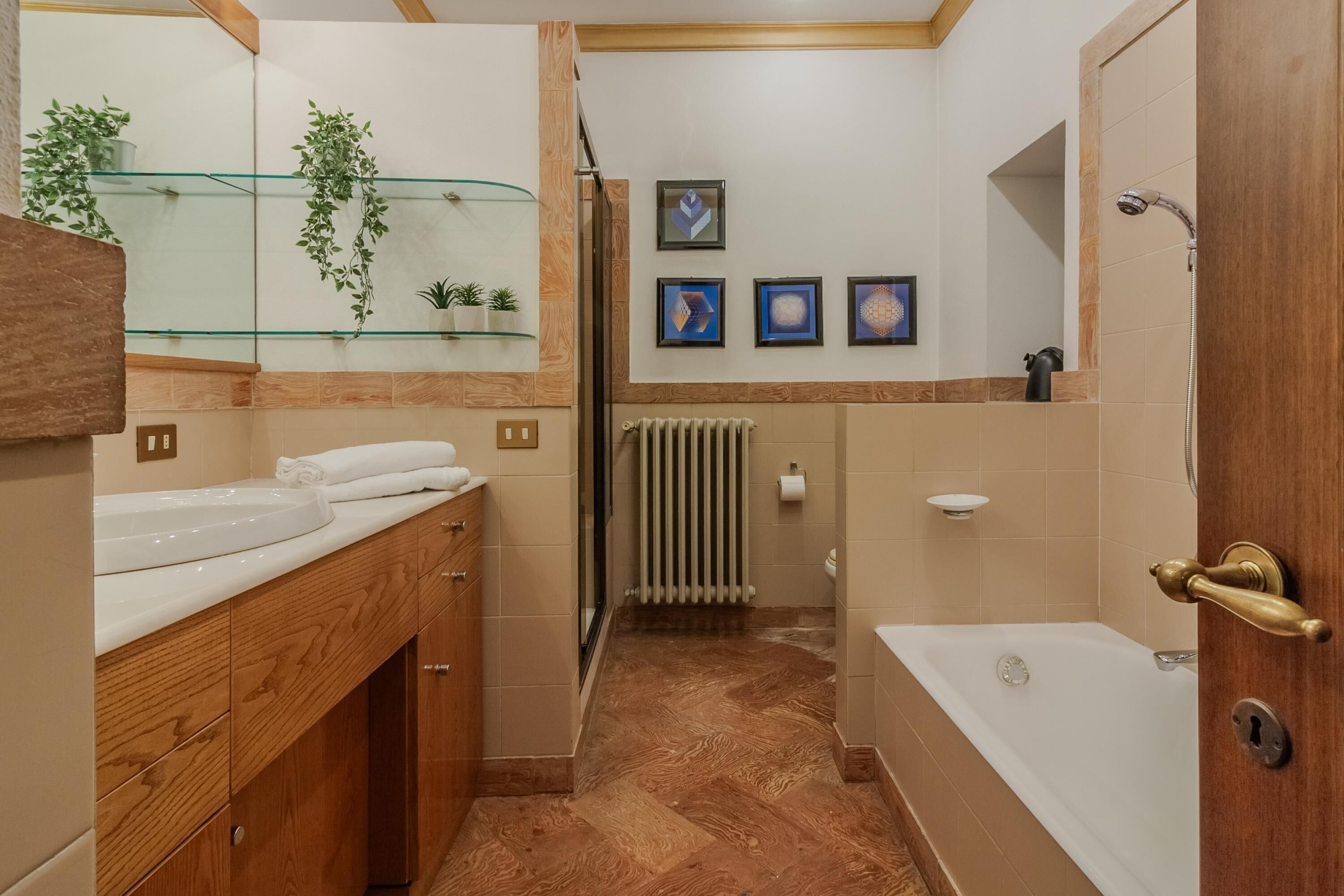 A modern bathroom with a wooden vanity, a glass shower enclosure, and a bathtub.
