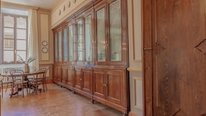 A dining area with a long wooden cabinet, a dining table with chairs, and a large window with curtains. - Miranda s Home in Varenna (Varenna)