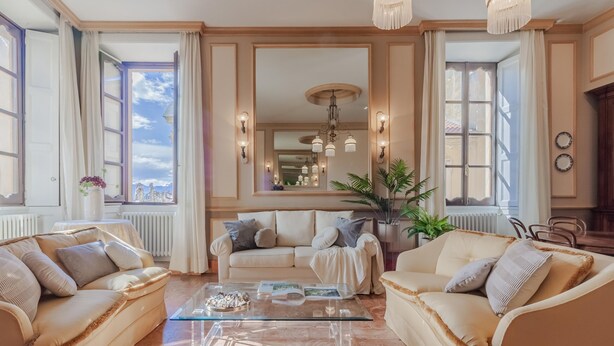 A spacious living room with two beige sofas, a glass coffee table, and a large mirror reflecting the room. - Miranda s Home in Varenna (Varenna)