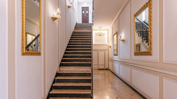 A grand staircase with ornate gold-framed mirrors on either side, leading to a door at the top. - Decimo Meridio- At Spanish Steps- (Rome)