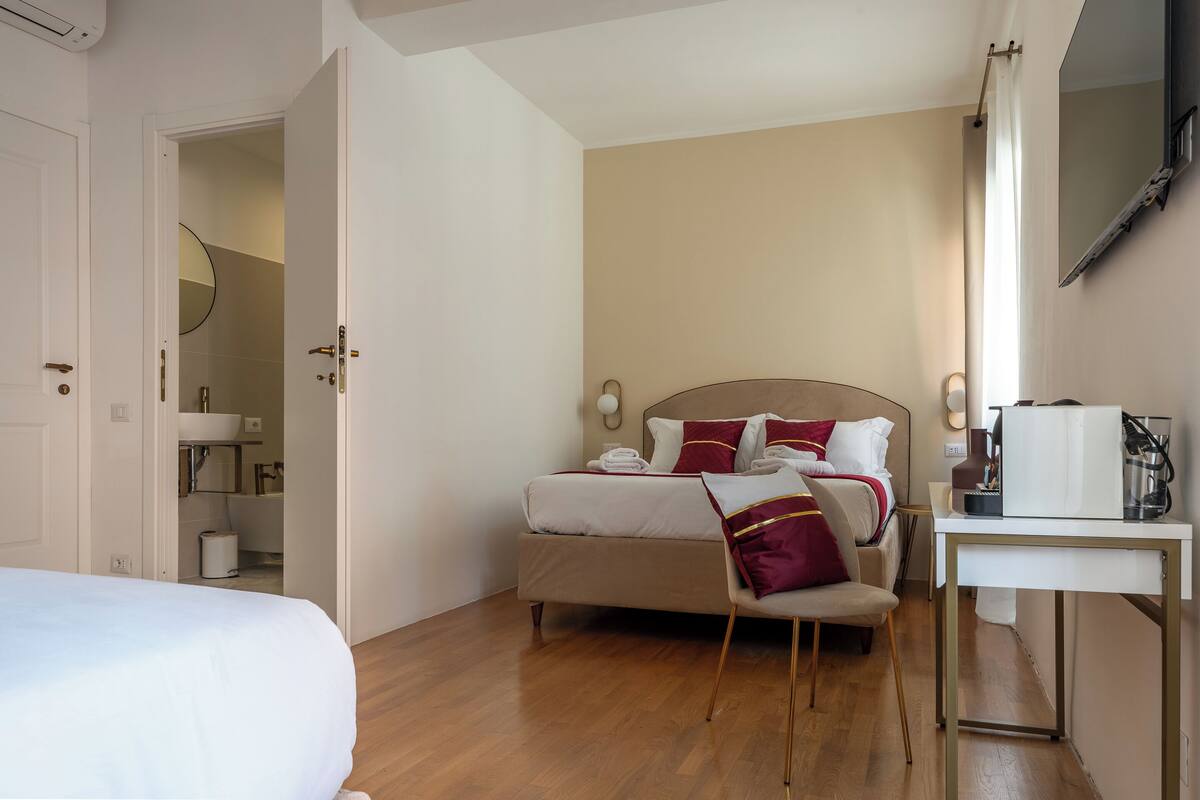 A hotel room with a bed, bedside table, and a view of the bathroom.