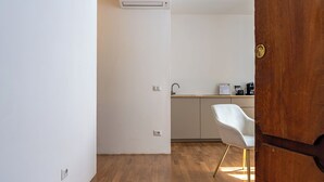 A modern kitchen with white cabinets, a wooden floor, and a white chair. - Decimo Meridio- At Spanish Steps- (Rome)