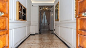 A hallway with marble flooring, wooden doors, and a chandelier. - Decimo Meridio- At Spanish Steps- (Rome)
