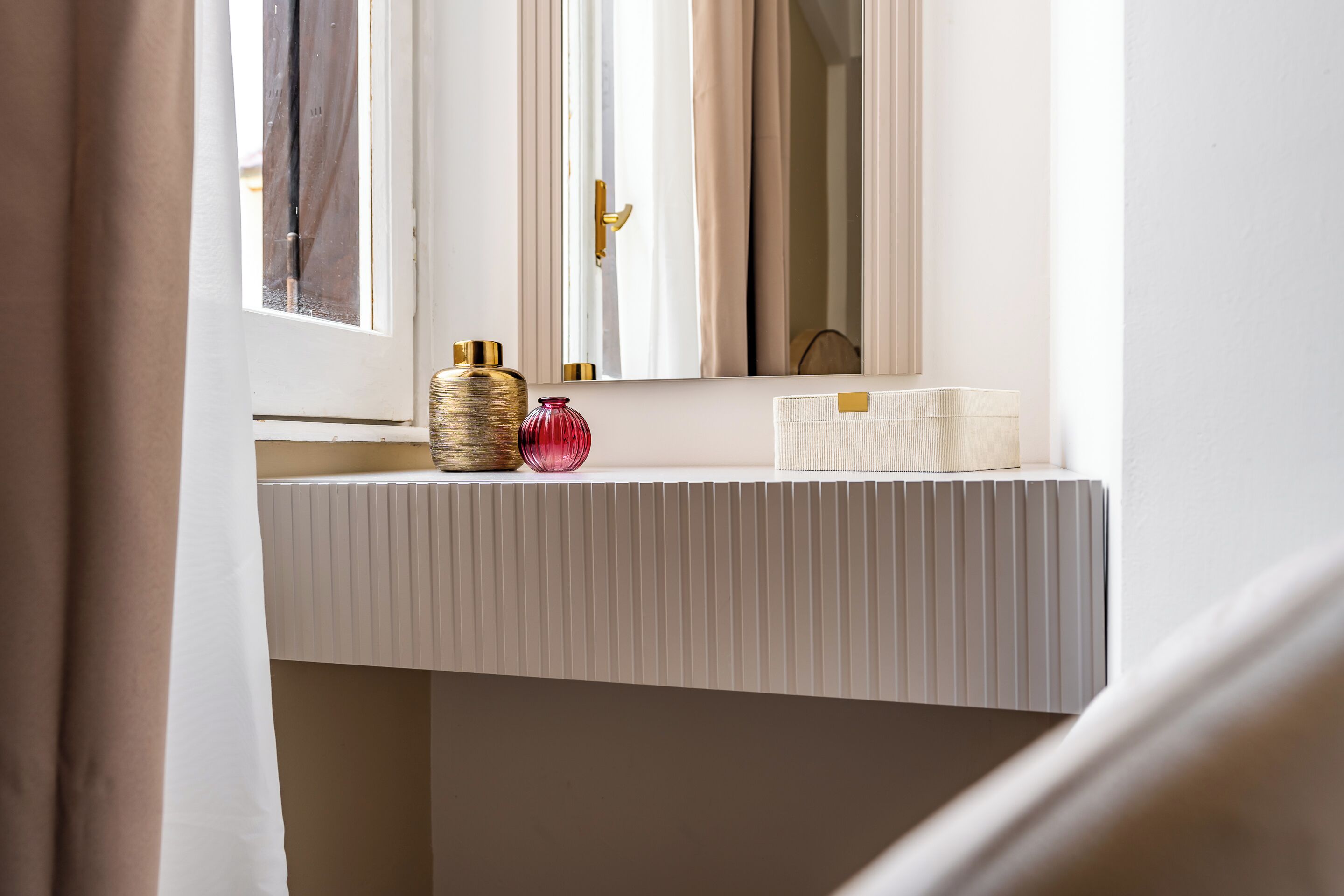 Un baño con mostrador blanco, espejo y dos botellas decorativas.