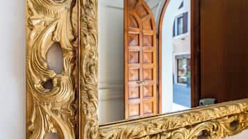 A gold-framed mirror reflecting a wooden door with a diamond pattern.