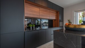 Eine moderne Küche mit dunklen Schränken, einer Holz Arbeitsplatte und Blick auf die Stadt.