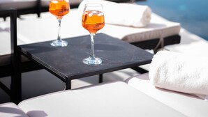 Ein Poolbereich mit zwei Gläsern Orangensaft, einem weißen Handtuch und Liegestühlen.