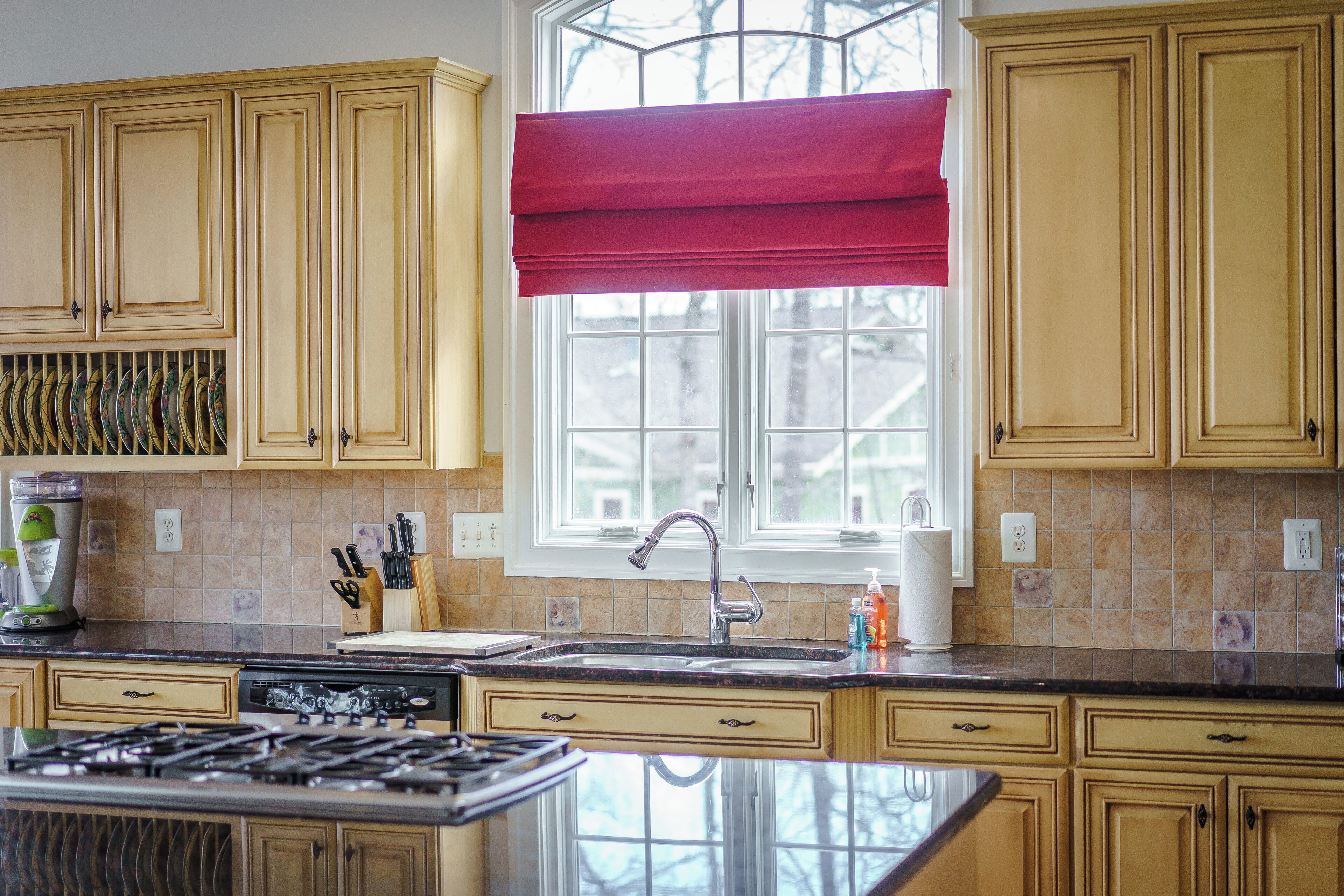 A kitchen with wooden cabinets, a stainless steel sink, and a gas stove.