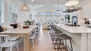 Et rummeligt køkken med en stor ø, moderne hårde hvidevarer og udsigt til opholdsstuen.