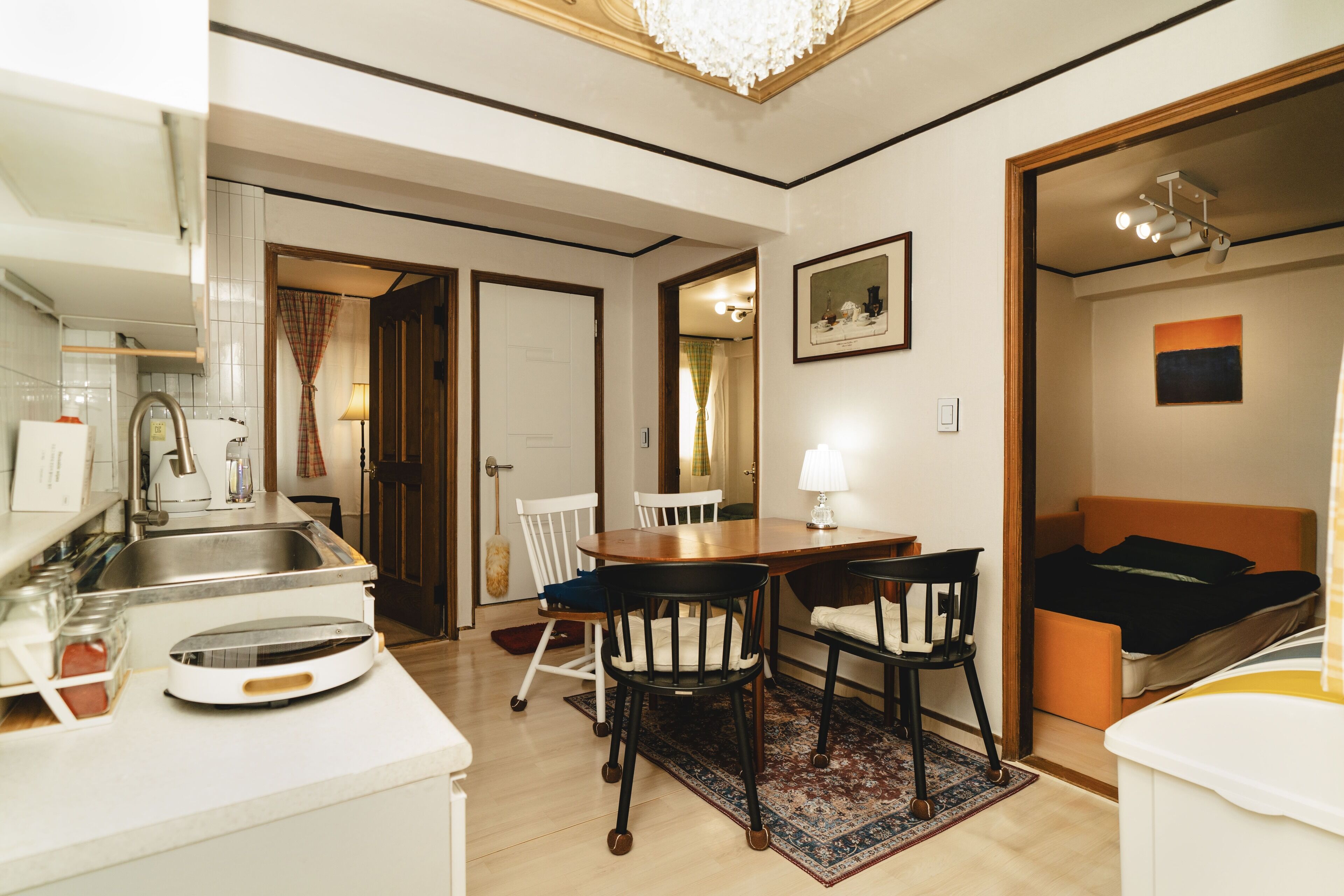 A compact living space with a kitchenette, a dining area with chairs, a bed, and a small bathroom.