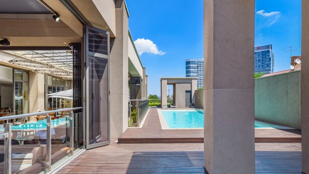 Una terrassa exterior amb piscina, portes de vidre i mobiliari d'exterior.