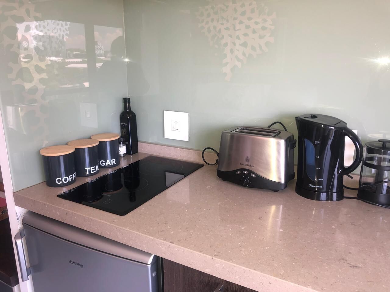A kitchen with a countertop, a toaster, a coffee maker, and three containers labeled 'Coffee', 'Tea', and 'Gar'.