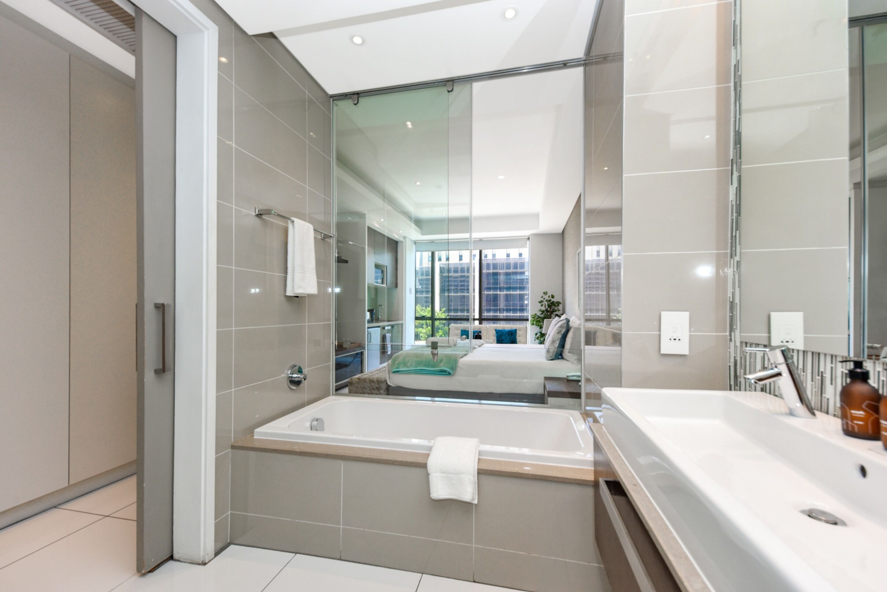 A modern bathroom with a large bathtub, a separate shower area, and a large mirror reflecting the room.