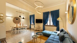 A modern living room with a sofa, a dining table, and a TV. - Fabulous apartment with a panoramic terrace in the historic center. Elevator (Firenze)