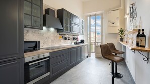A modern kitchen with dark cabinets, a microwave, and a built-in oven. There is a bar area with stools and a wine rack holding bottles. - Fabulous apartment with a panoramic terrace in the historic center. Elevator (Firenze)