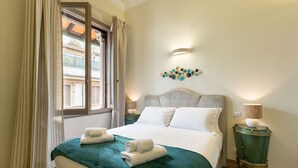 A hotel room with a bed, a nightstand, a wall-mounted light, and a window with curtains. - Fabulous apartment with a panoramic terrace in the historic center. Elevator (Firenze)