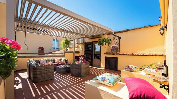 An outdoor patio with wicker furniture, a pergola, and hanging plants. - Fabulous apartment with a panoramic terrace in the historic center. Elevator (Firenze)