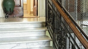 A marble staircase with a wrought iron railing leading to a room with wooden doors and a green pot on the floor. - Fabulous apartment with a panoramic terrace in the historic center. Elevator (Firenze)