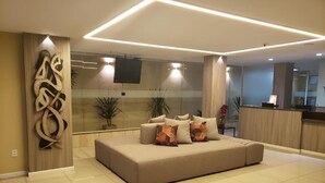 A modern living room with a beige sofa, decorative wall art, and a glass partition. - Villa Park Fortaleza (Fortaleza)