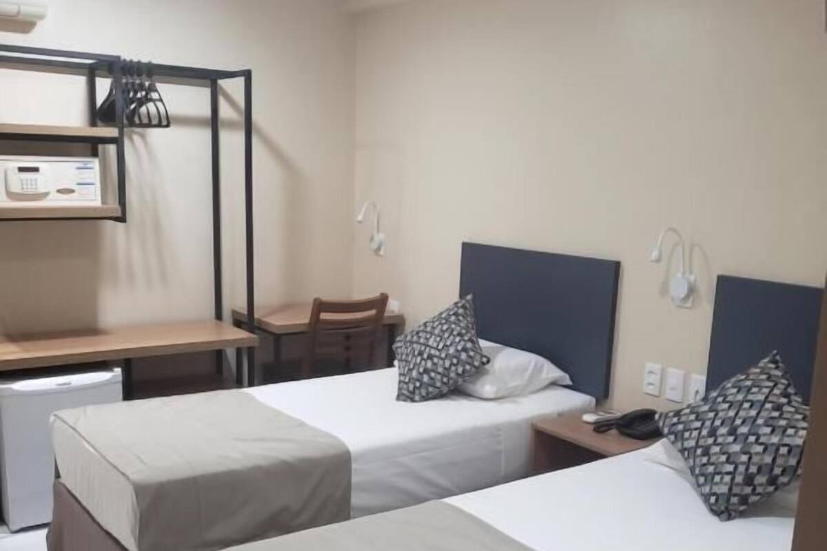 A hotel room with two beds, a desk, and a chair.