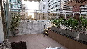 A balcony with wicker furniture, potted plants, and a glass table. - Villa Park Fortaleza (Fortaleza)