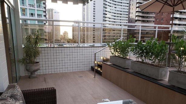 A balcony with wicker furniture, potted plants, and a glass table. - Villa Park Fortaleza (Fortaleza)