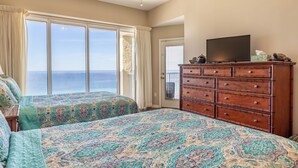 A bedroom with two beds, a dresser, a television, and a view of the ocean. - 2BR 2BA Penthouse Condo at the Long Beach! (Panama City Beach)
