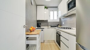 Una cucina moderna con mobili bianchi, un piano di lavoro in legno, forno a incasso e microonde.