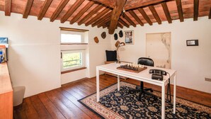 Ein Zimmer mit Holzboden, einem Schachbrett auf einem Tisch, einem Schreibtisch, einem Stuhl, einem Fenster und einem Teppich.