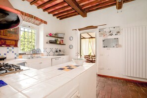 A kitchen with a central island, a stove, and a window. There is a door leading to another room. - A detached villa from the 1800s, 250 square meters in size, completely renovated. Ocean view. (Lucca)