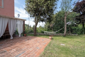 A patio with a hammock, a covered seating area, and a stone wall.