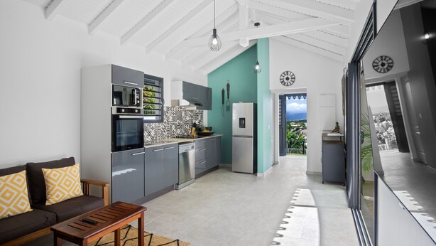 Une cuisine moderne avec des meubles gris, un four encastré et un mur d’accent de couleur turquoise.