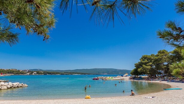 A beach with clear blue water, pebbly shore, and trees. - Holiday house EMY with pool in Krk 600m from the beach (Krk)