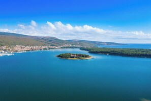 Eine Luftaufnahme einer Küstenstadt mit einer markanten Insel, auf der ein einzelnes Gebäude steht.