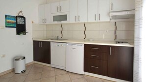 Una cocina moderna con gabinetes blancos y marrón oscuro, lavavajillas, microondas y una campana extractora de acero inoxidable.